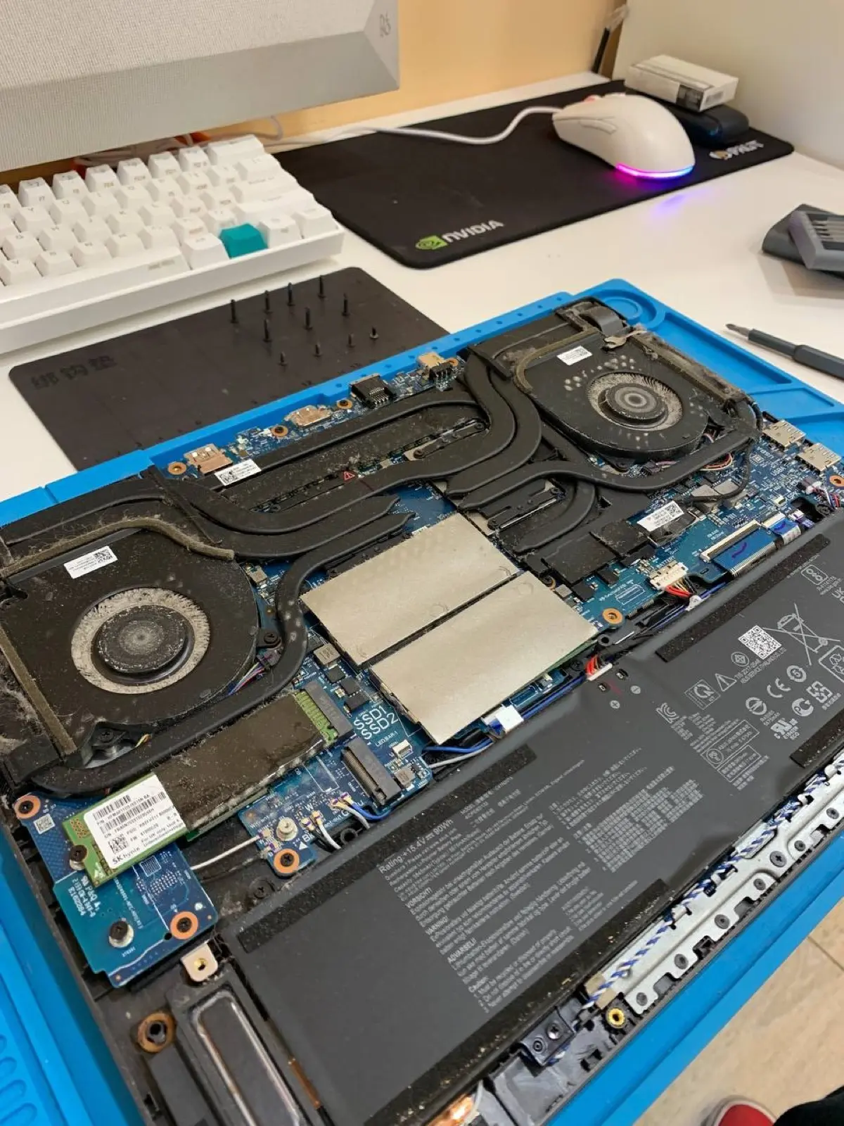 Разобранный игровой ноутбук ASUS ROG на антистатическом коврике: два вентилятора, тепловые трубки, снятая крышка